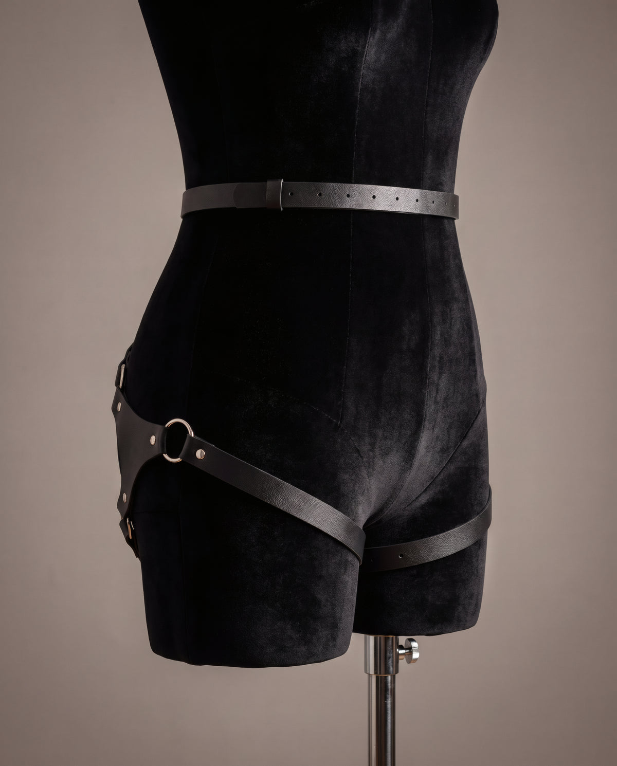 Harnais Circé sur buste velours noir, vue côté face : ceinture fine et sangle en diagonale sur la cuisse