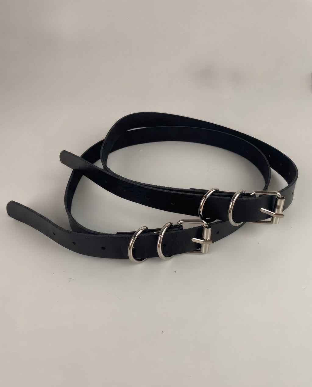 La paire de jarretières Lilith seule : cuir vegan noir, boucle argentée et deux anneaux en D