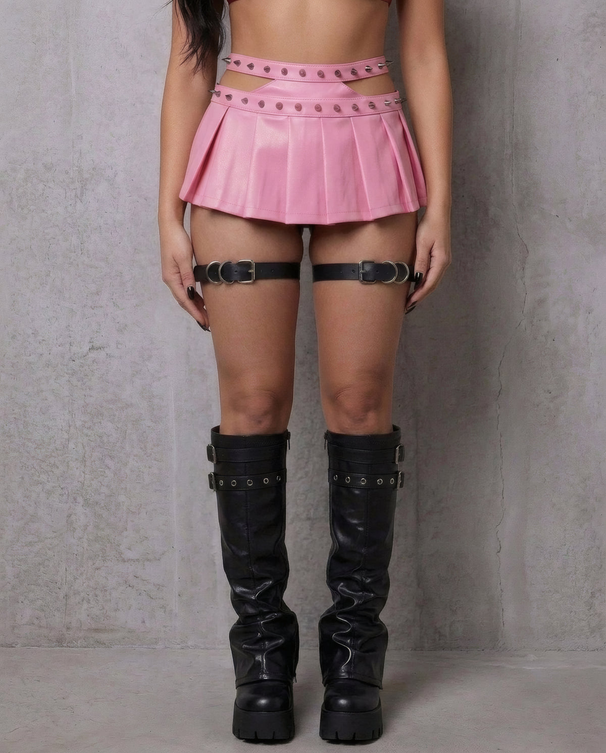 Jarretières Lilith portées de face avec micro-jupe plissée rose cloutée et bottes noires