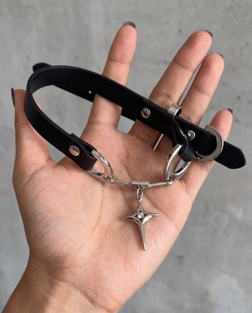 Collier Stella posé dans une main : bande en cuir vegan, attaches argentées et étoile