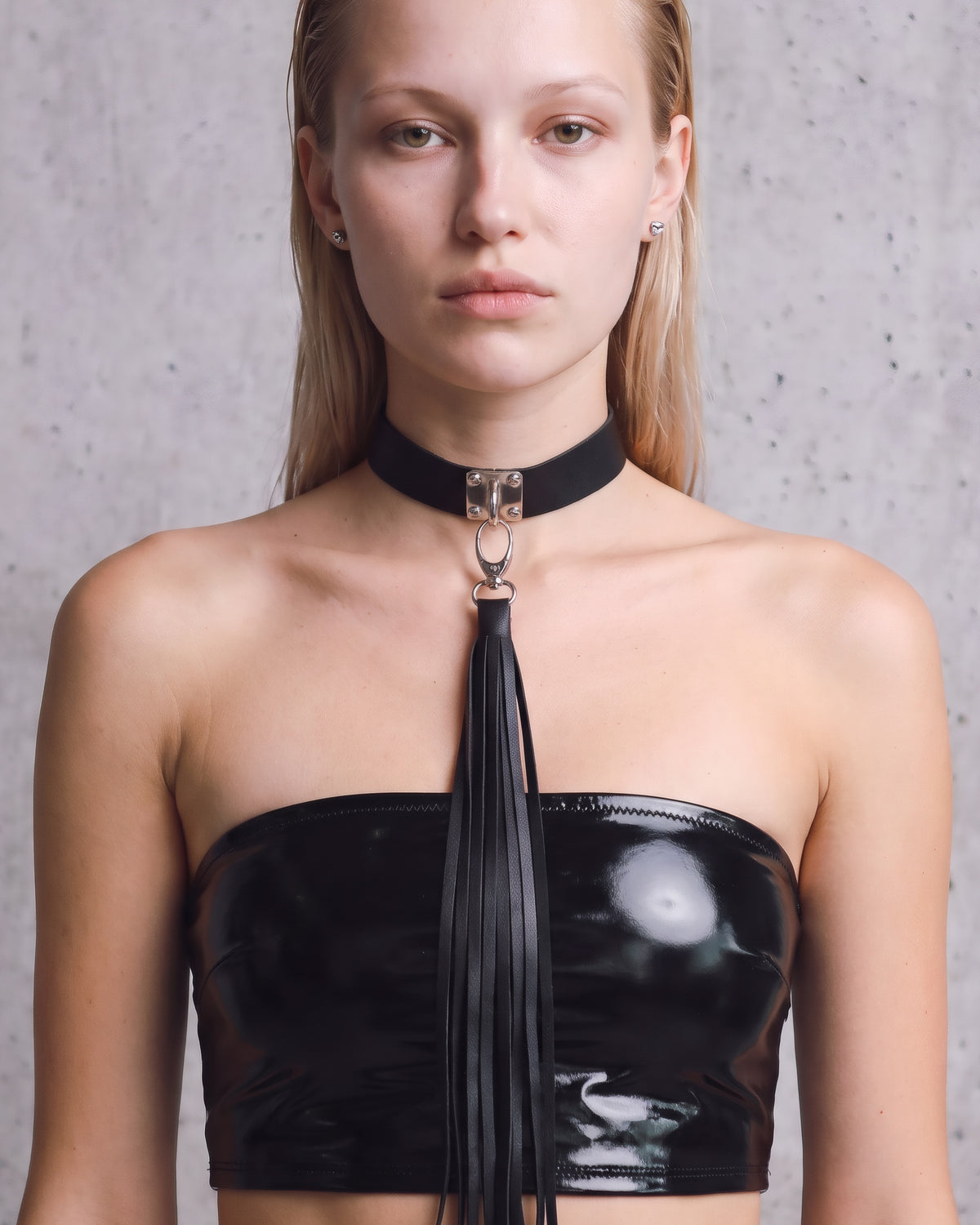 Collier ras-de-cou Zelda en cuir vegan noir à plaque argentée et long pompon de franges, porté de face avec un bandeau en vinyle noir